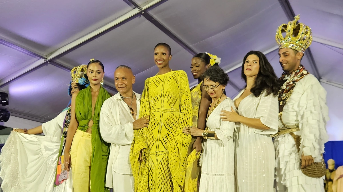 Des mannequins et leurs tenues blanches, jaunes et vertes sur le podium du défilé de CARIFESTA XV.